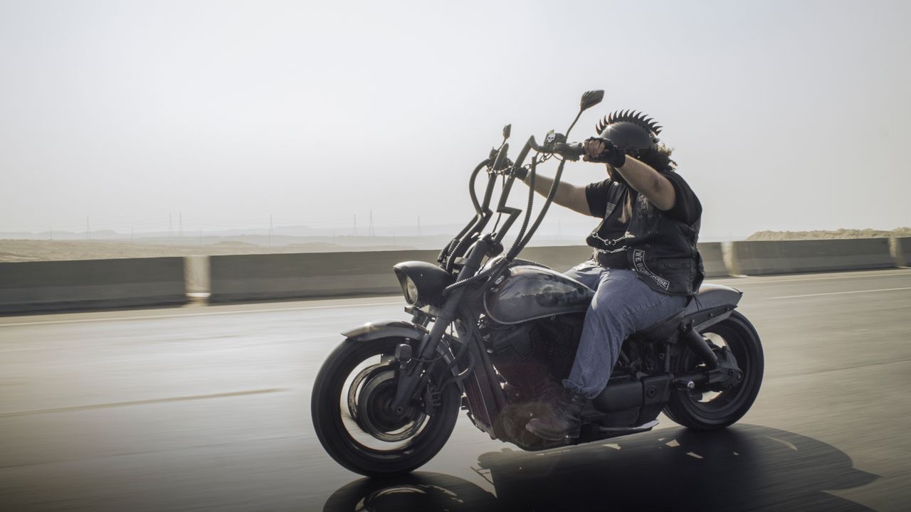 about-02 Rider on a custom motorcycle cruising down a highway, showcasing freedom and adventure.