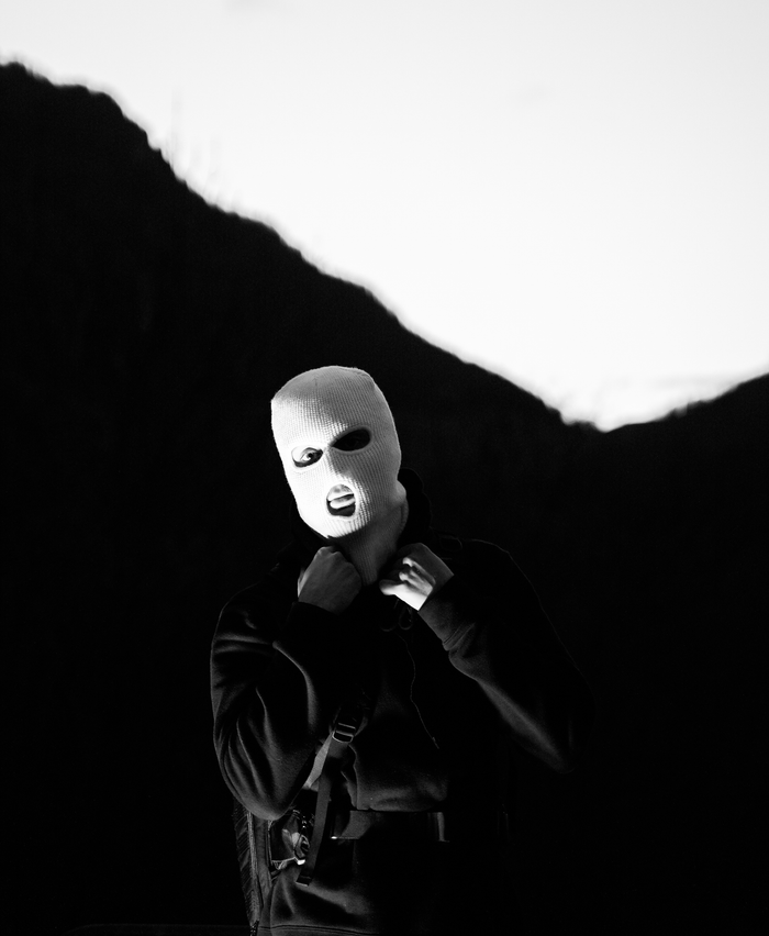 services-02 Foreboding black and white image of a masked figure against a dramatic mountain silhouette.