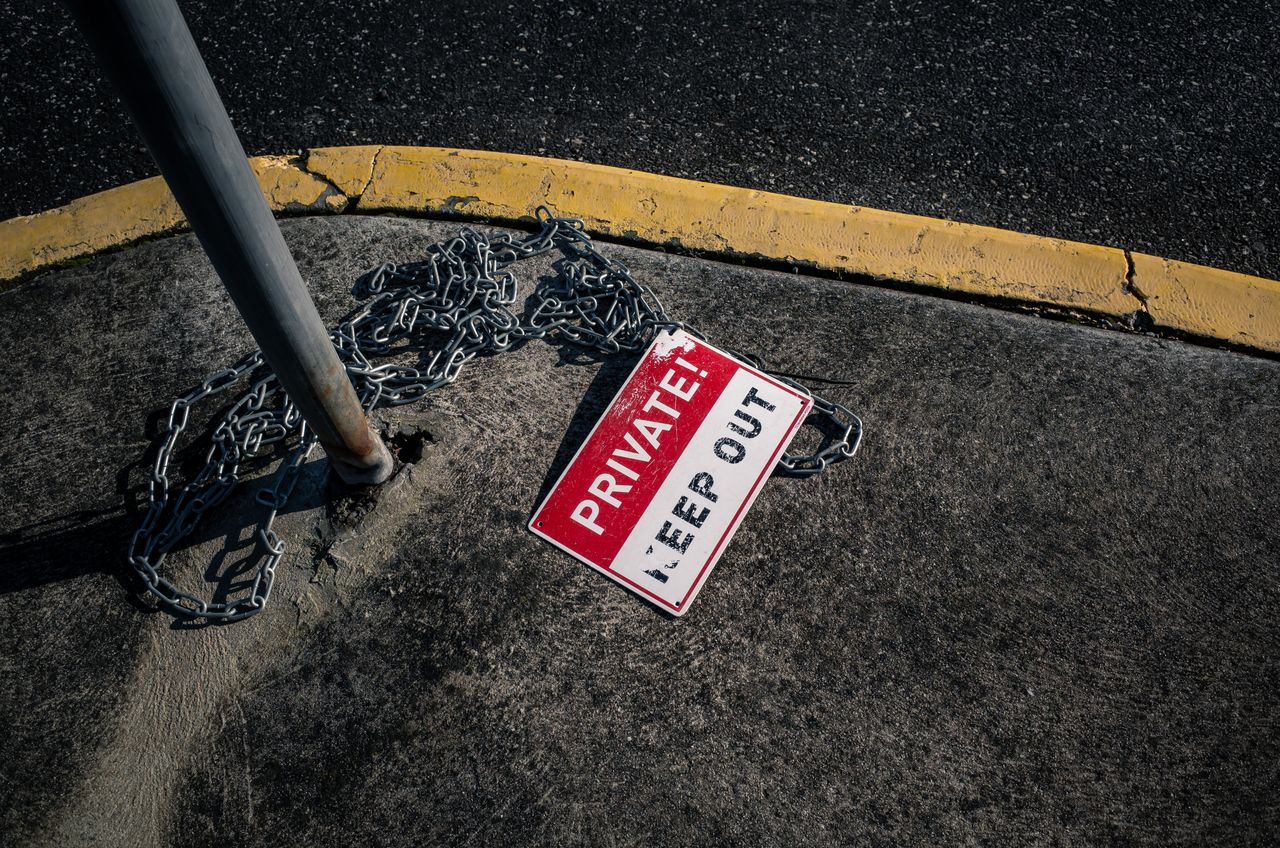 about-img A chained 'Private Keep Out' sign lies on an urban sidewalk, emphasizing security.